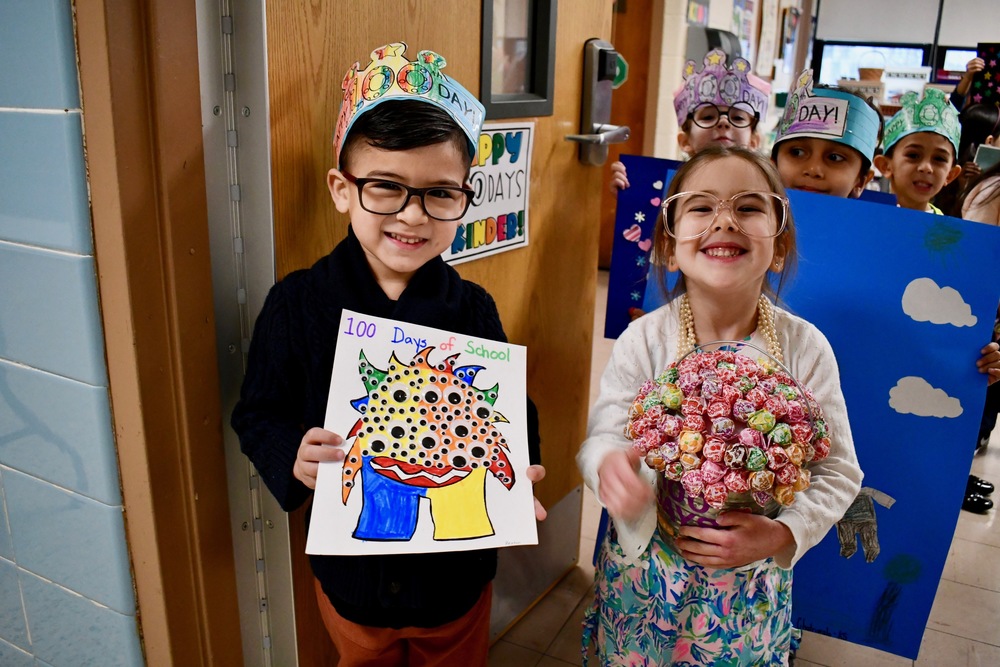 Two students smiling with their 100th Day of School projects