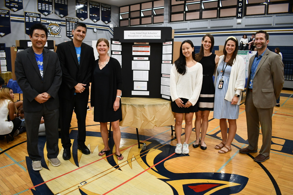 AP Research student with administrators and teachers in front of research poster