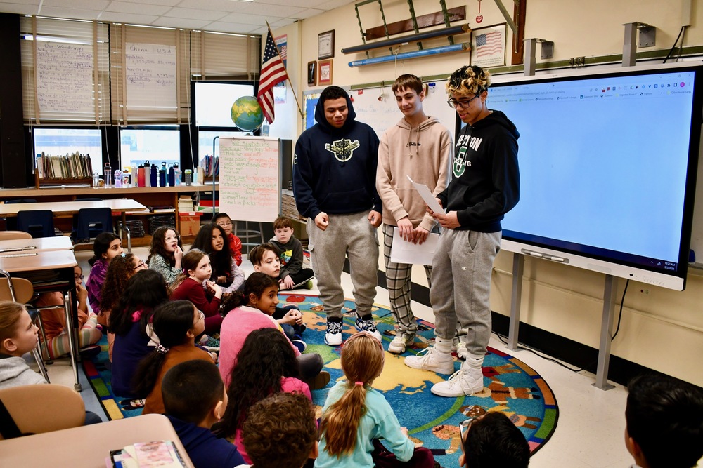 Three high school students speaking with elementary class