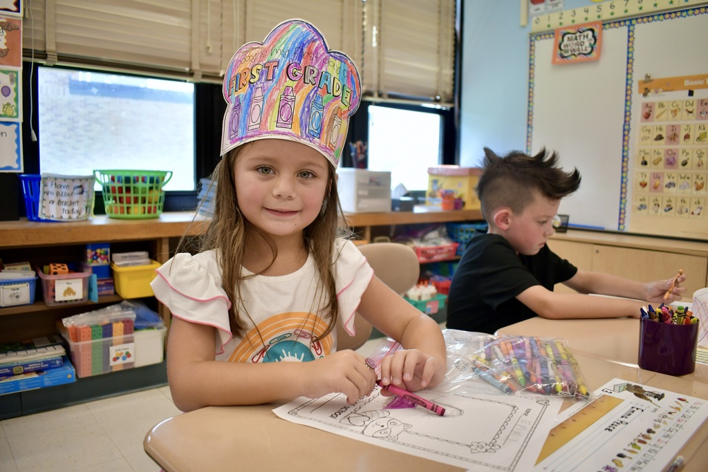 Girl smiling with First Grade hat on
